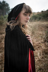 Young woman with long hair, in black cloak with red lining