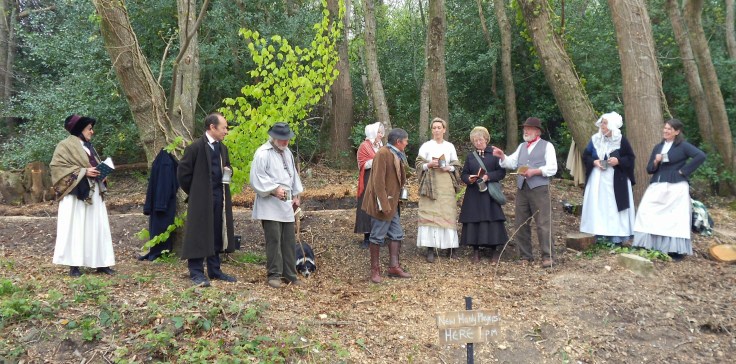 Group of people in nineteenth century costume in a woodland setting